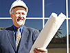 A man wearing a hardhat and holding blueprints